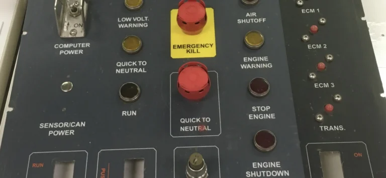 Printed control panel overlay with labeled switches and an emergency kill button