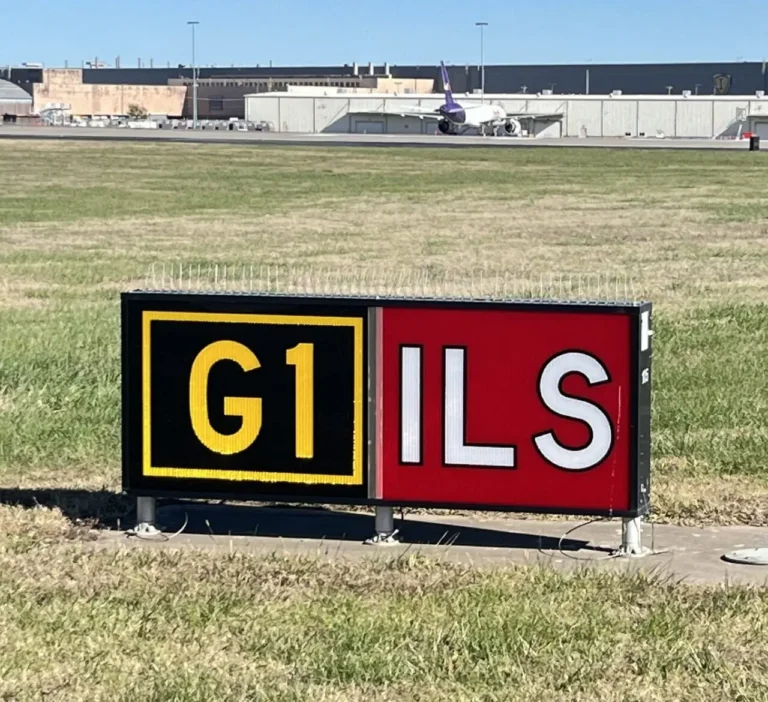 Lighted G1 ILS airfield sign beside an airport runway